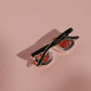 Colgante de gafas unisex con la montura de plata y chapada en oro negro. Los cristales son un cuarzo rojo con dendrítas. Las patillas están chapadas en oro negro.
