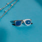 Colgante con forma gafas cuya montura es de plata y las patillas están chapadas en oro negro. Las lentes son la piedra calcedonia azul.