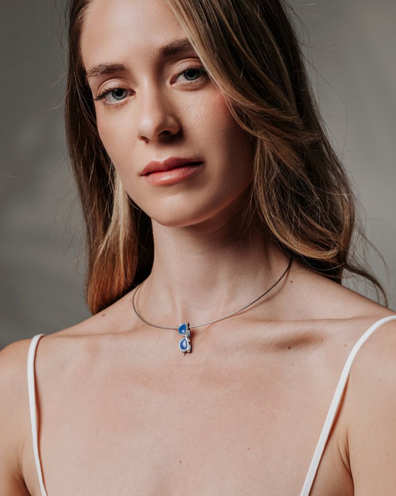 Colgante con forma de gafas de plata sostenible con calcedonia azul, chapadas en oro negro.